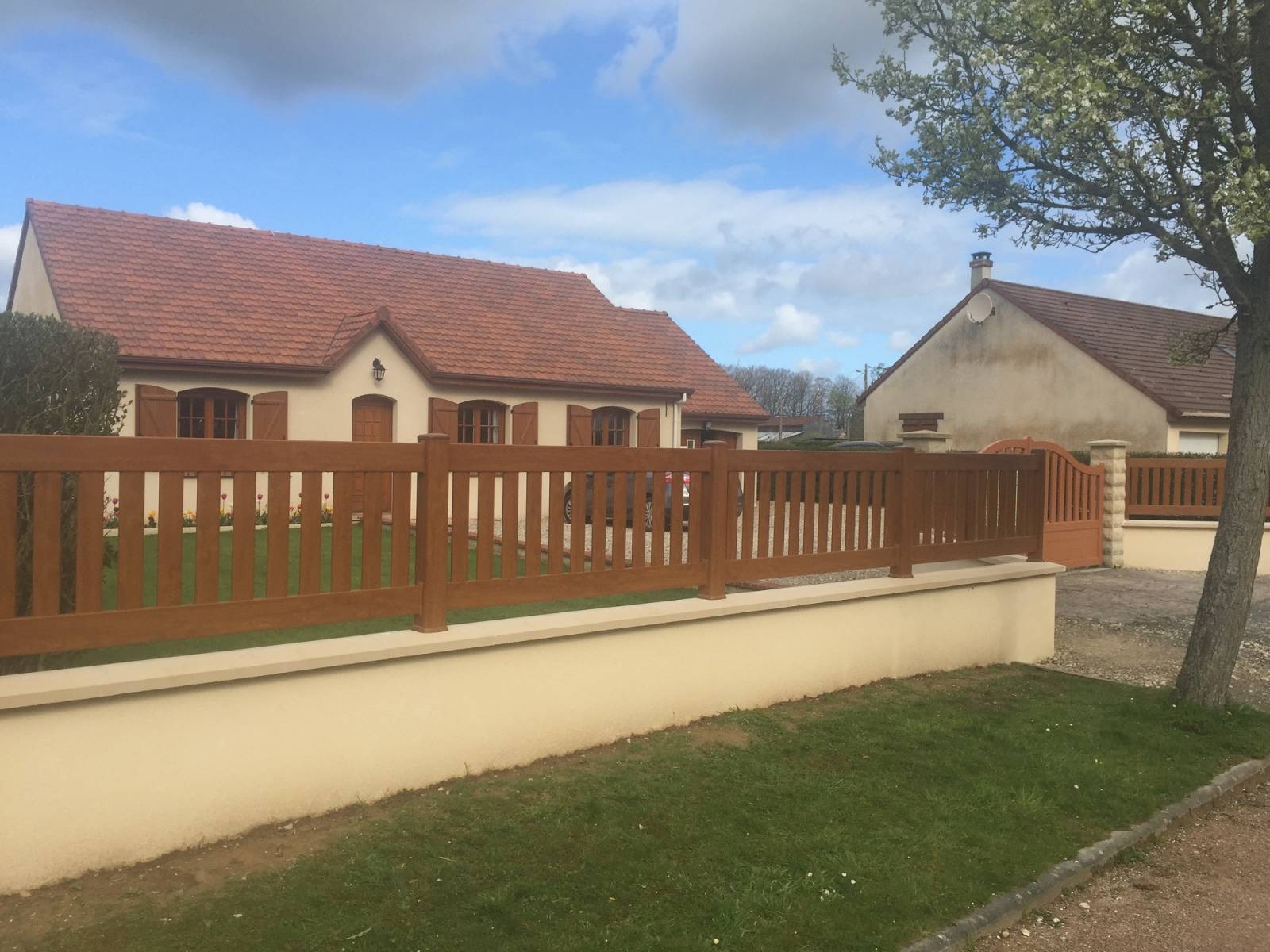 Réalisation d'un mur de clôture avec soubassement en agglos et barrière PVC couleur chêne doré proche Valmont 76
