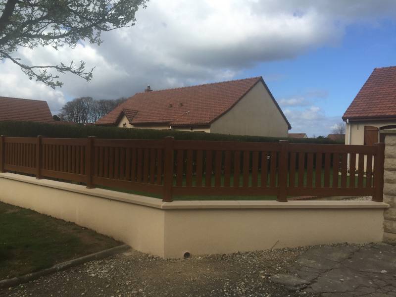 Réalisation d'un mur de clôture avec soubassement en agglos et barrière PVC couleur chêne doré proche Valmont 76